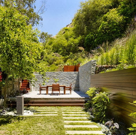 Cercos perimétricos para casas, diseños en diferentes materiales | Constructora Paramount Cerco de piedra que contiene en su interior una terraza, al costado madera Foto: John Maniscalco Architecture